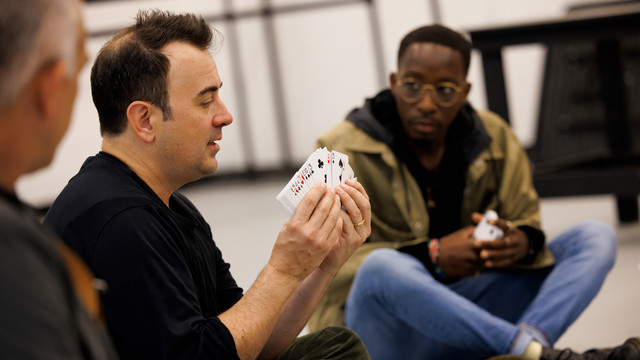 illusionist demonstrates a card trick to students