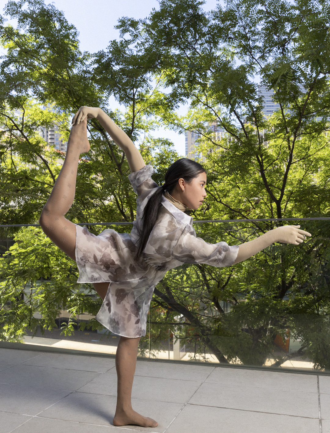 A dancer wearing Fendi attire poses outside on one leg