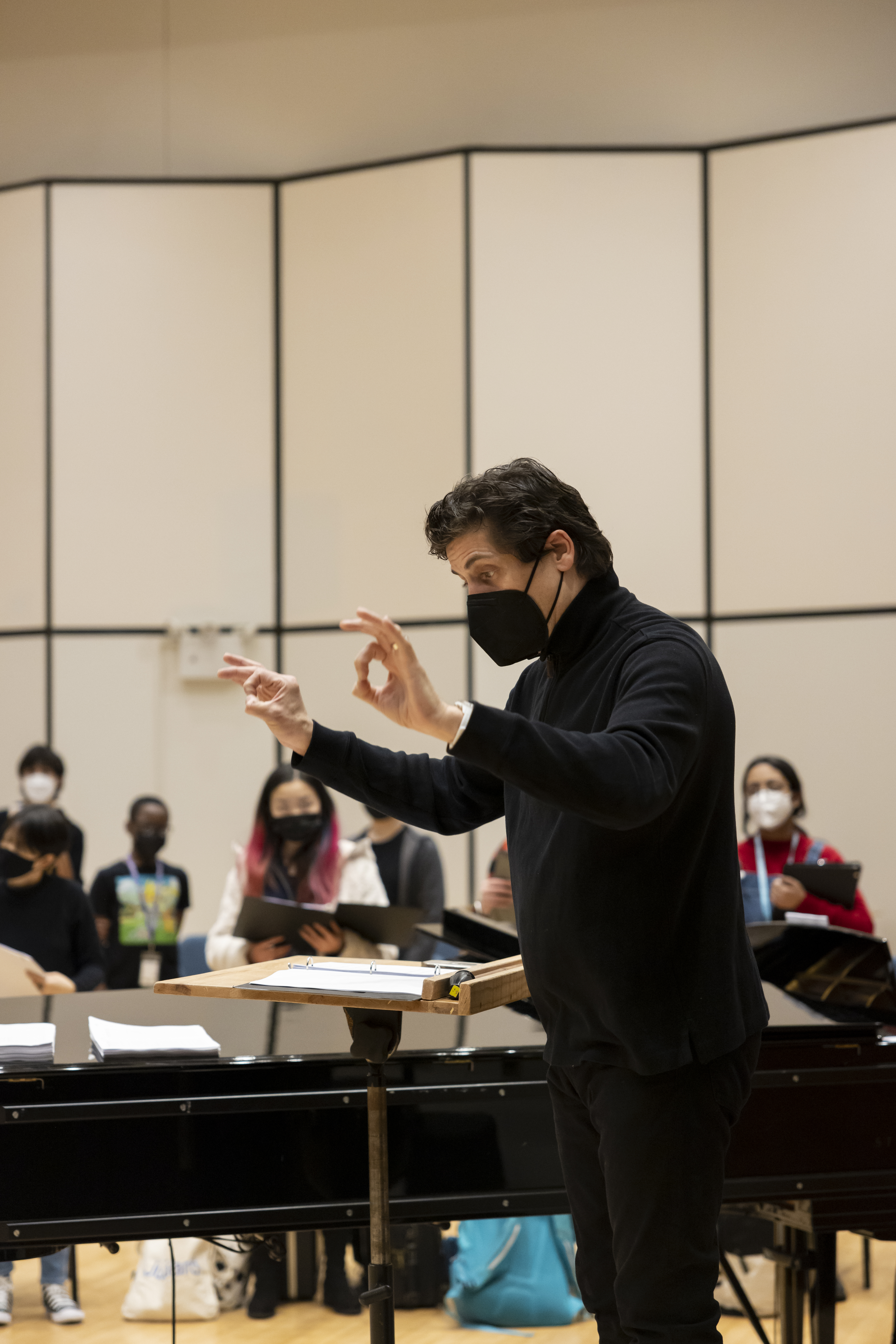 Francisco Nuñez is conducting MAP musicians during rehearsal in a candid photograph