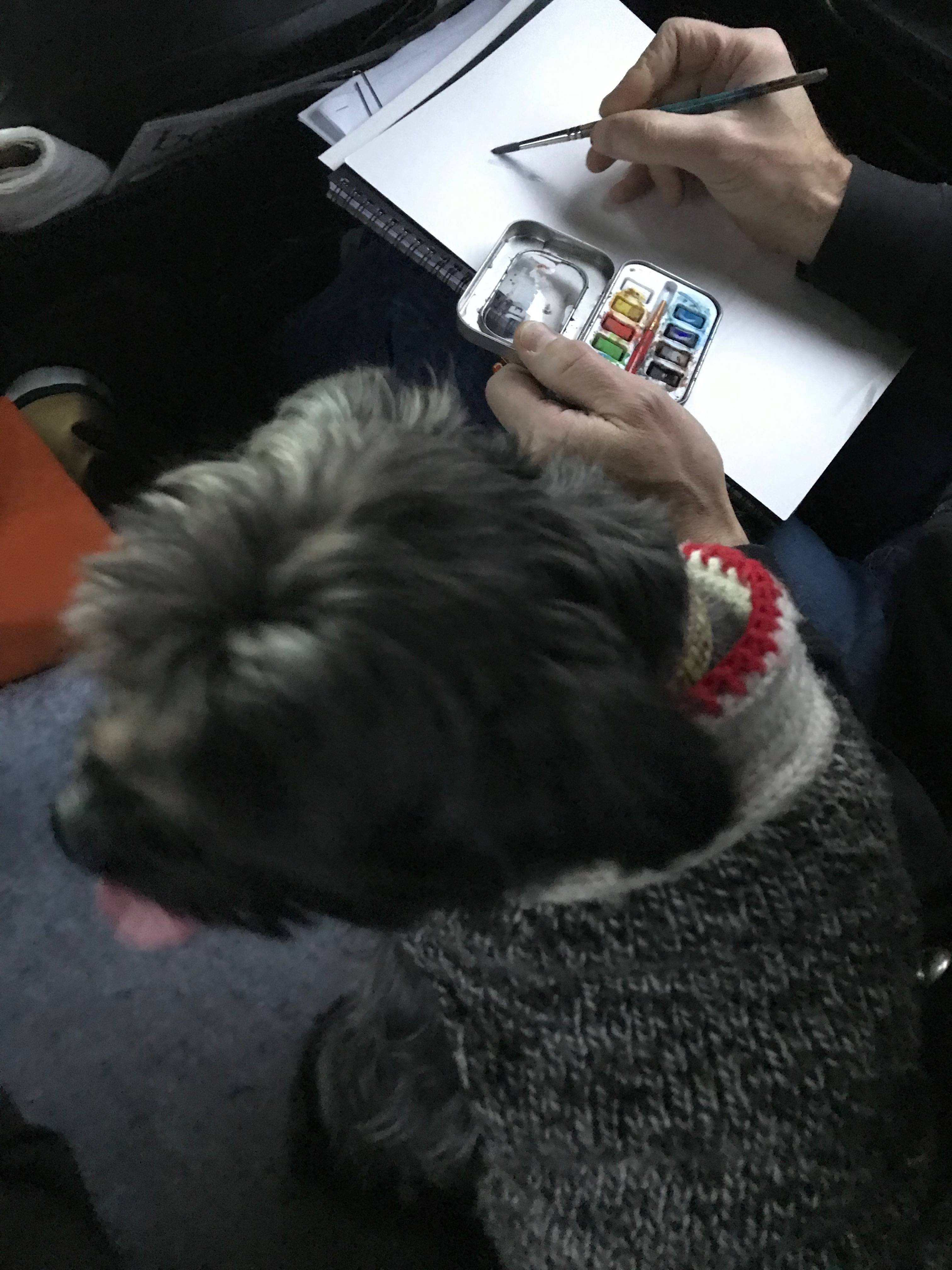 A man painting while a dog sits beside him