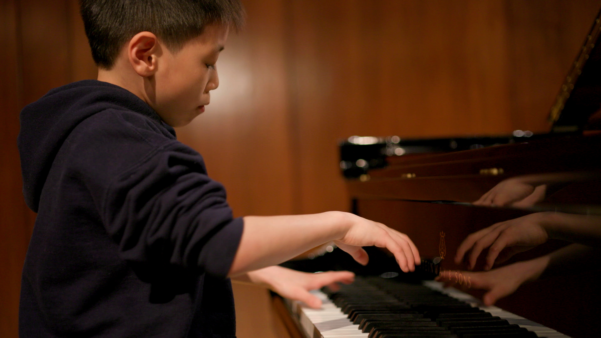 A young person playing piano in a cinematic still image
