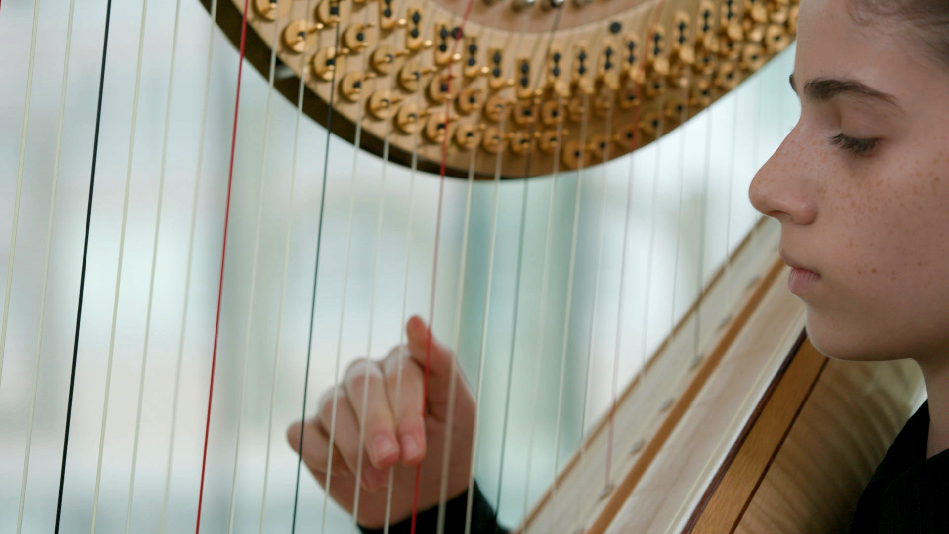 A young person playing harp in a cinematic still image
