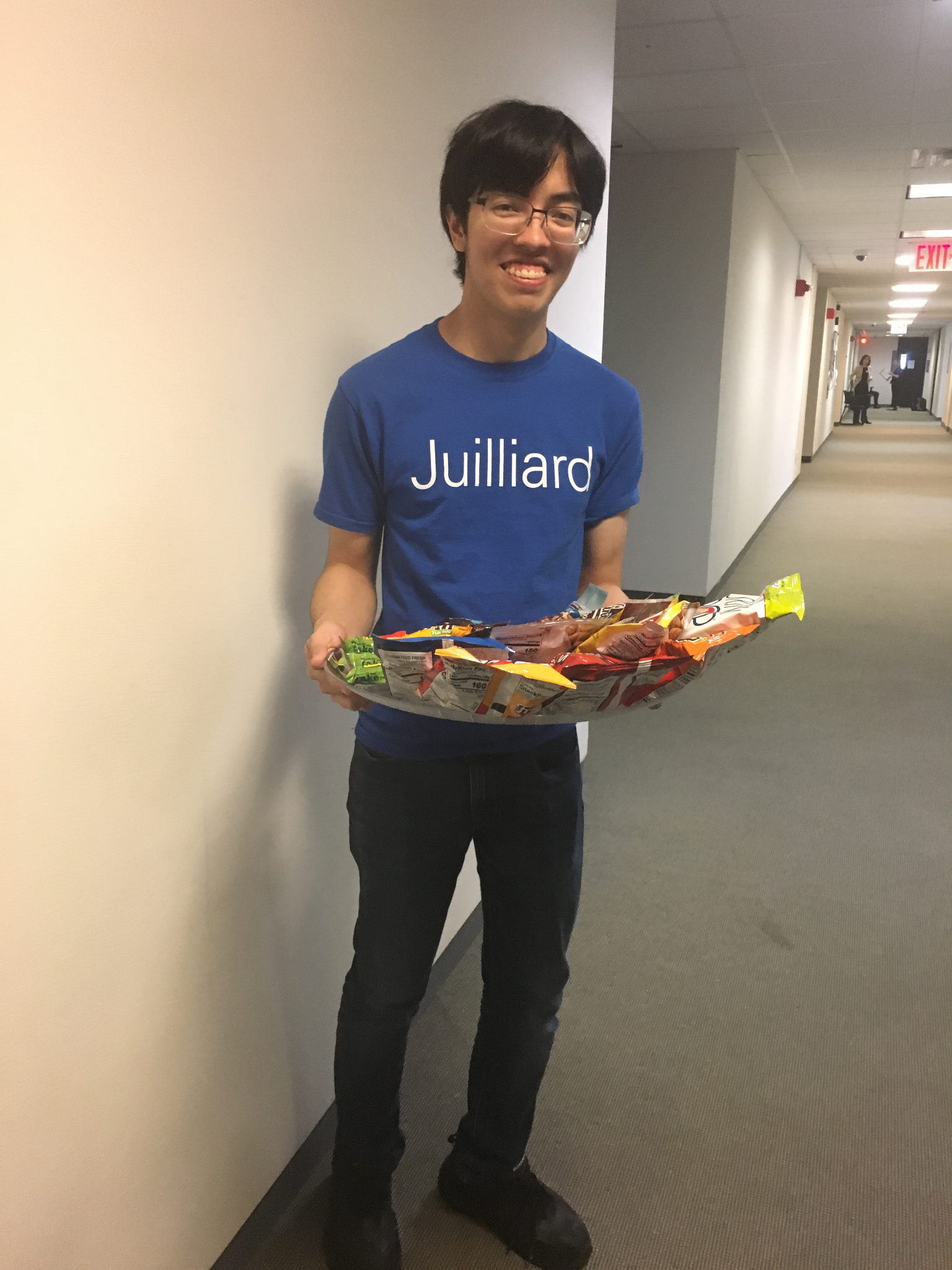 A student in a Juilliard t-shirt stands holding snacks