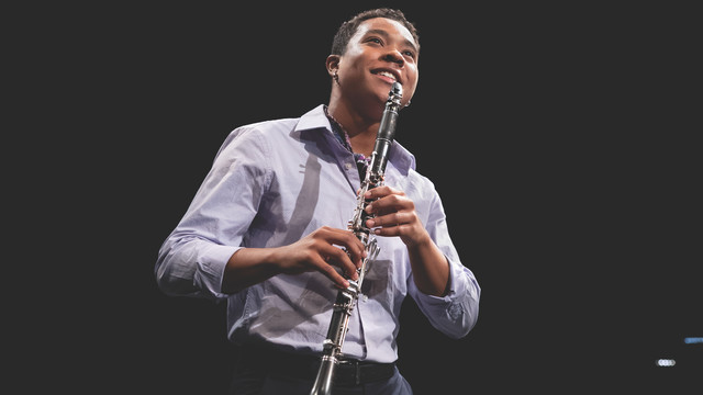 a young man holding a clarinet