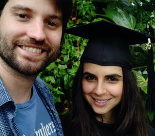 Georgeanne Banker, smiling, in her cap and gown posing with her boyfriend