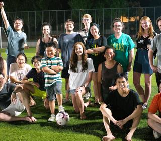 Students posing for a group photo in a field after playing soccer