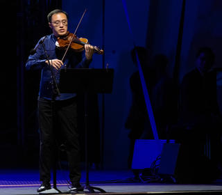 Max Tan on stage playing violin in a performance photo