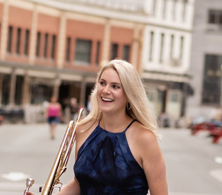 woman standing in the street with a trombone