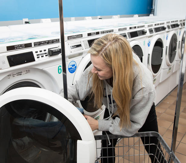 student loading laundry into a washing machine