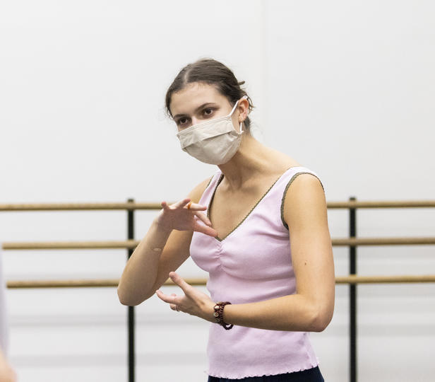 Flora Ferguson is demonstrating with a hand gesture during a rehearsal in a dance studio