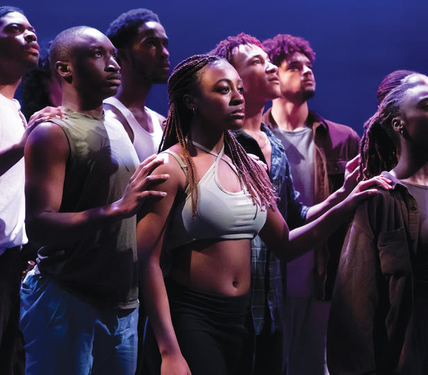 Students in a group on stage during a performance are gazing intently