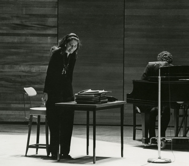 Black and white archival photo of Maria Callas on stage smiling toward the audience during a master class at Juilliard