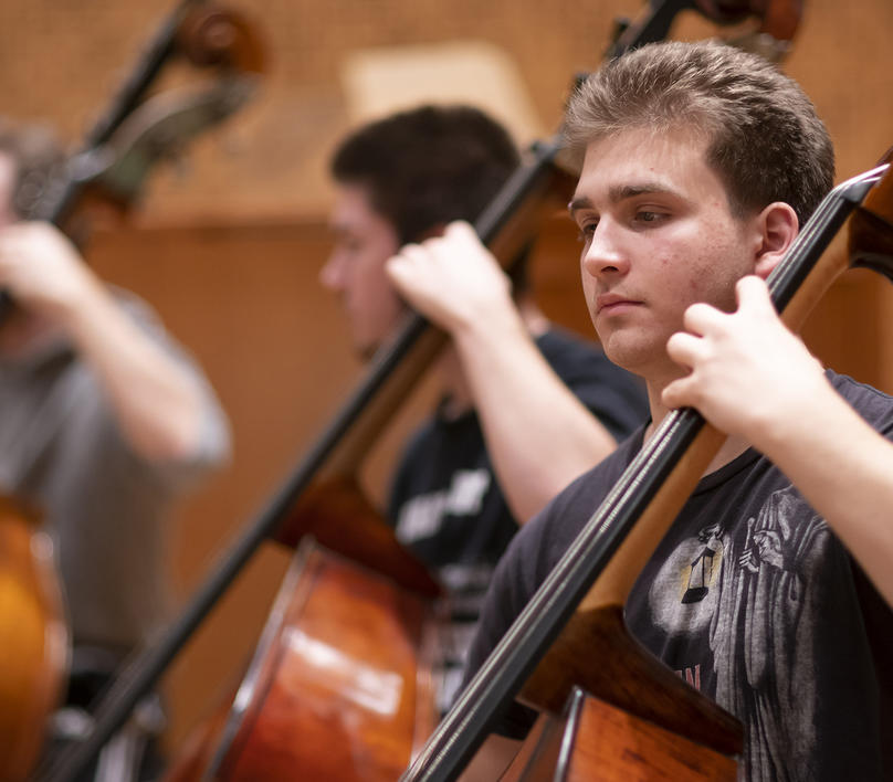 Students in an orchestra rehearsal with John Adams