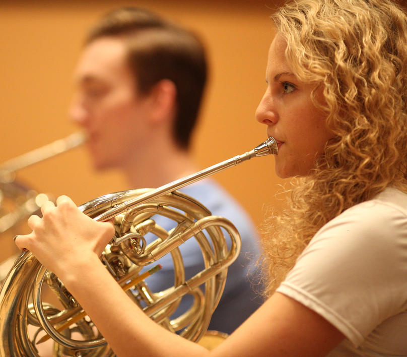 French Horn player in an orchestra rehearsal