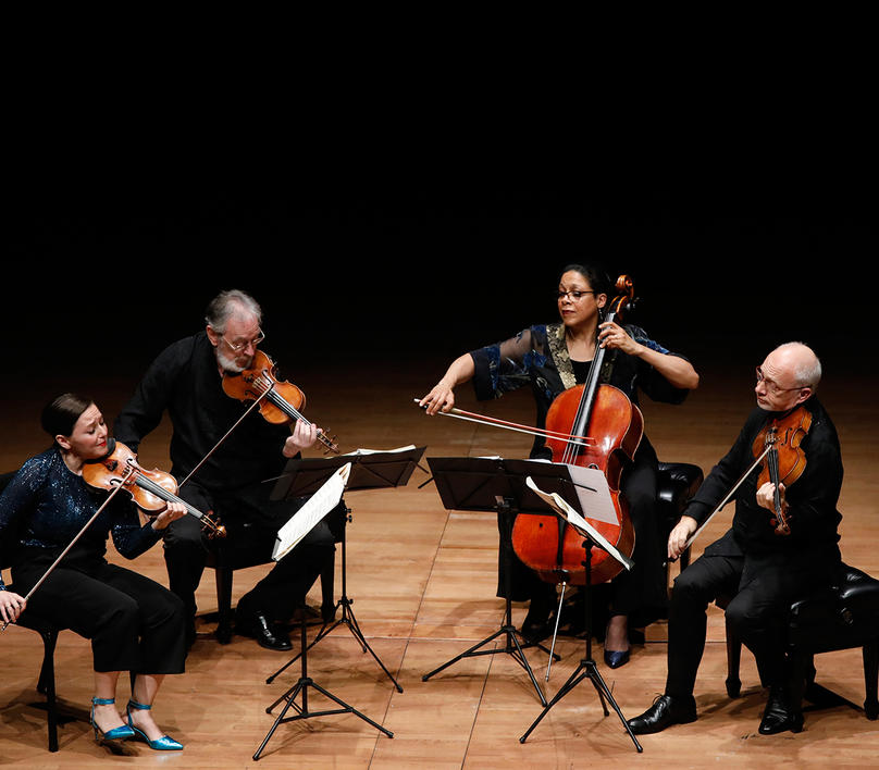 4 performers seated on stage playing instruments