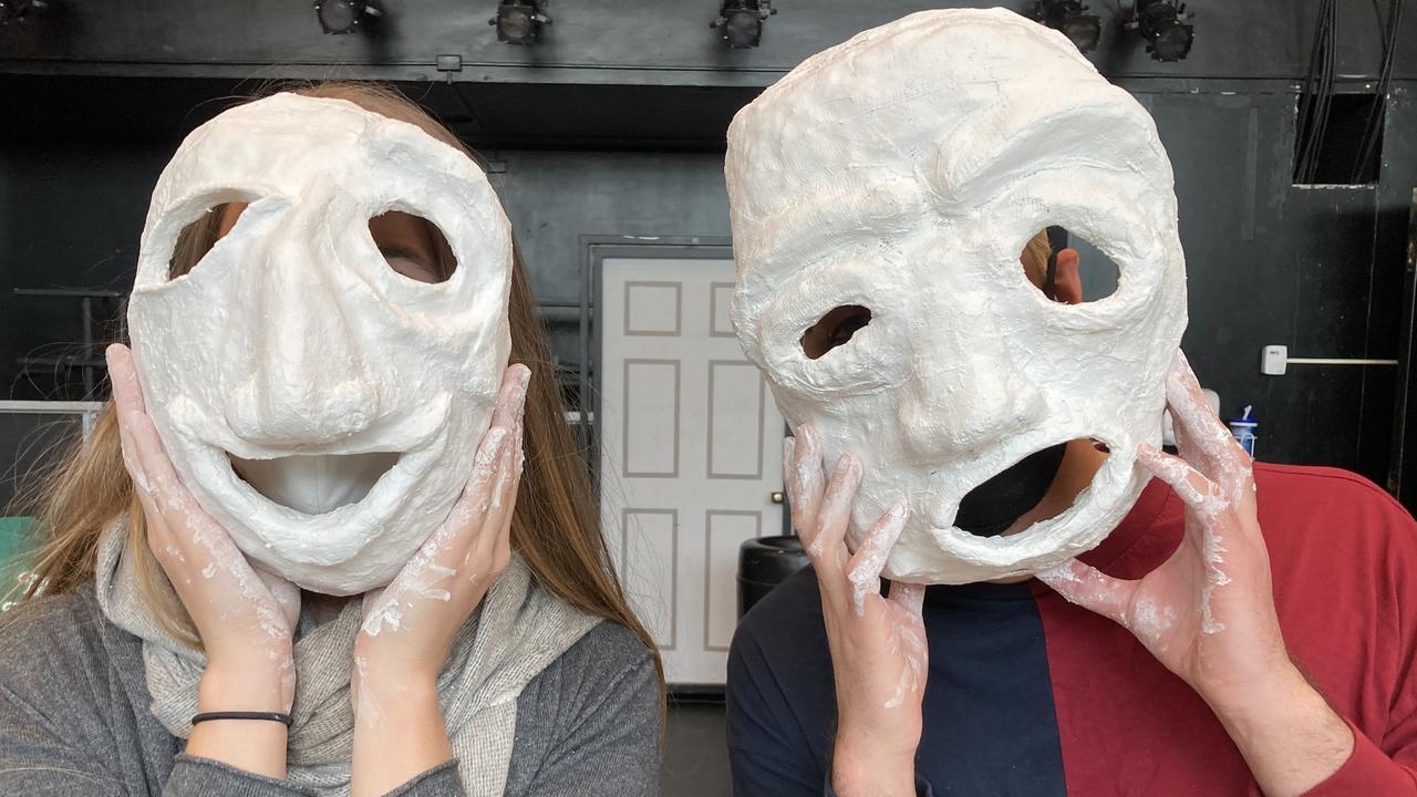 Two students show off the plaster masks they made for their drama class