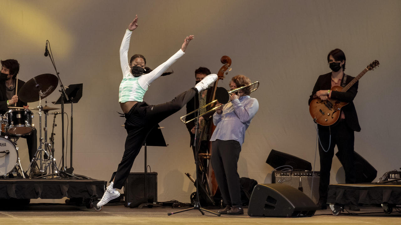 A dancer and a jazz musicians are on stage together, lending a feeling of interdisciplinary performance