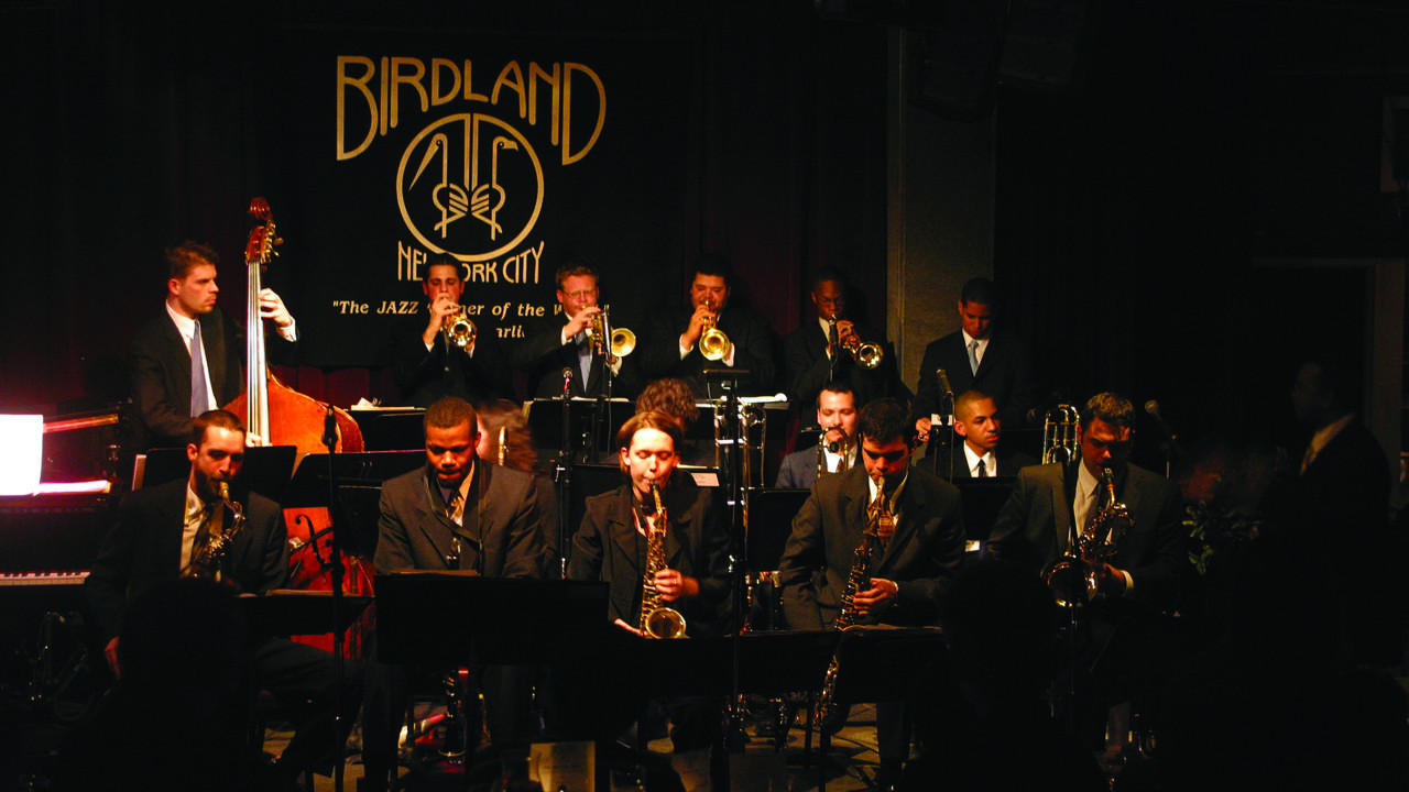 The Juilliard Orchestra is performing and a sign that reads "Birdland" is clearly displayed