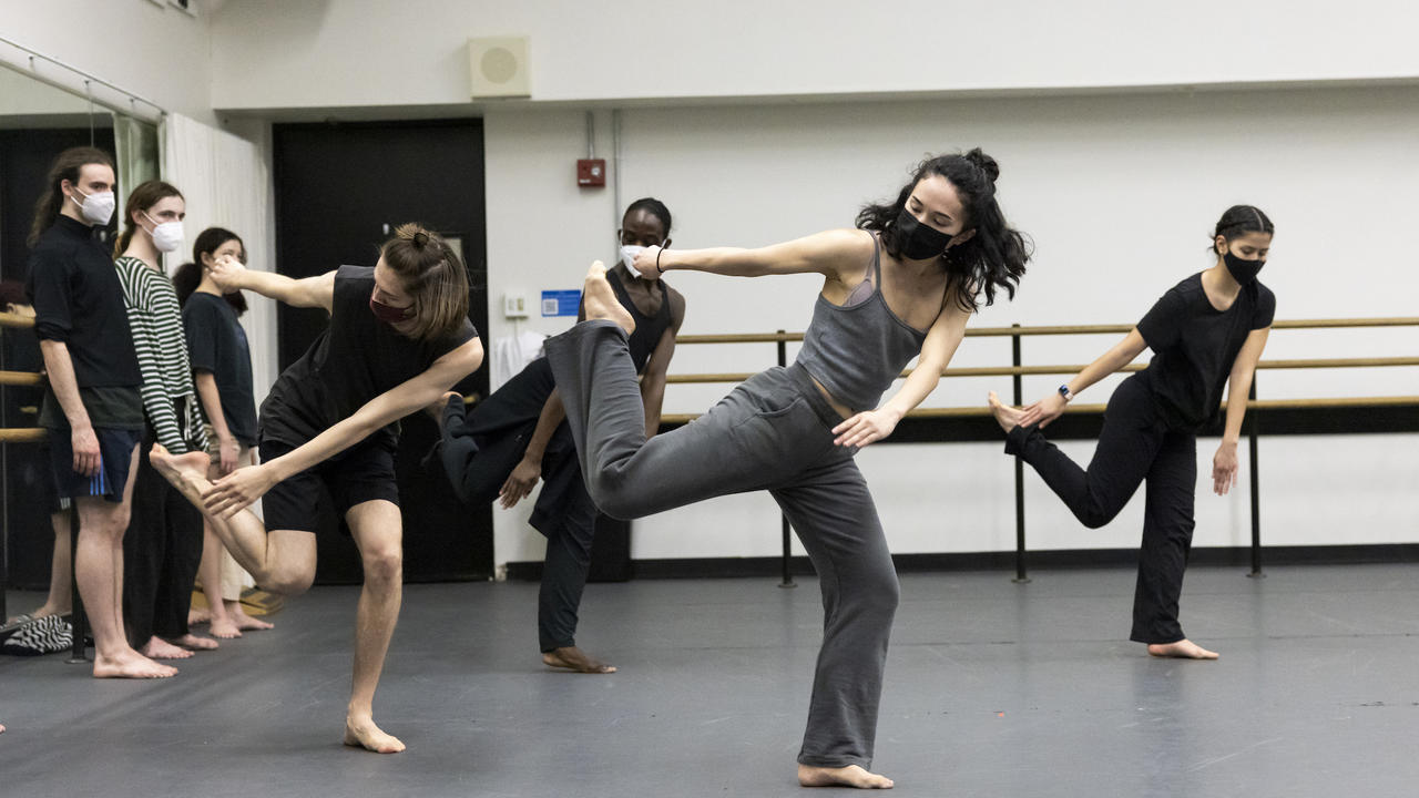 Group of dancers rehearsing in a dance studio while other dancers look on