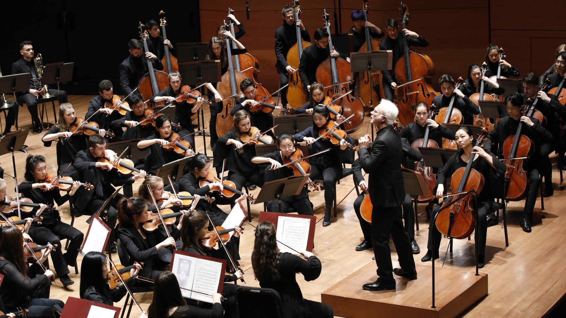 The Juilliard Orchestra performs on stage at Alice Tully Hall, conducted by John Adams