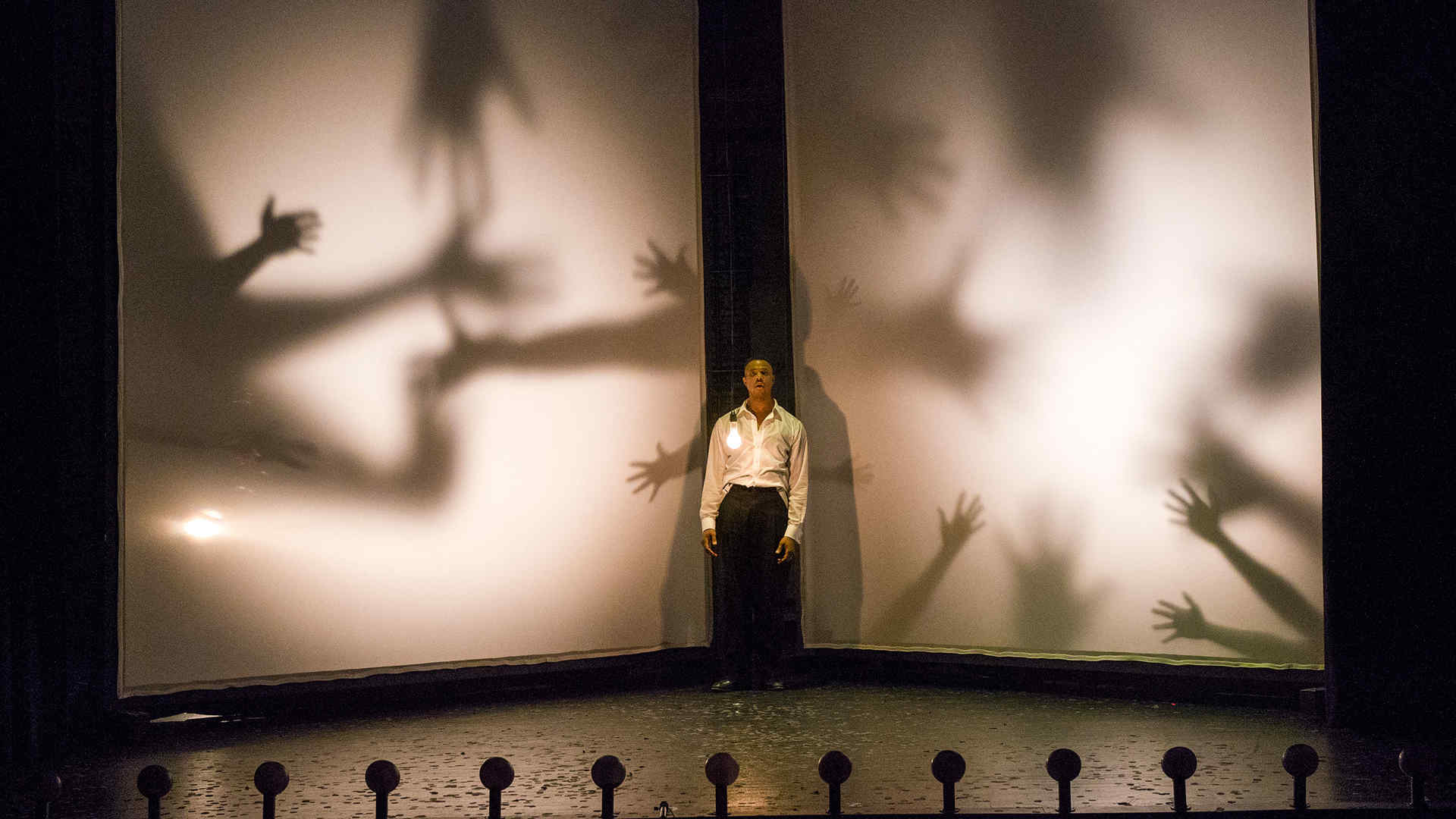 Man standing on stage with hand shadows in the background