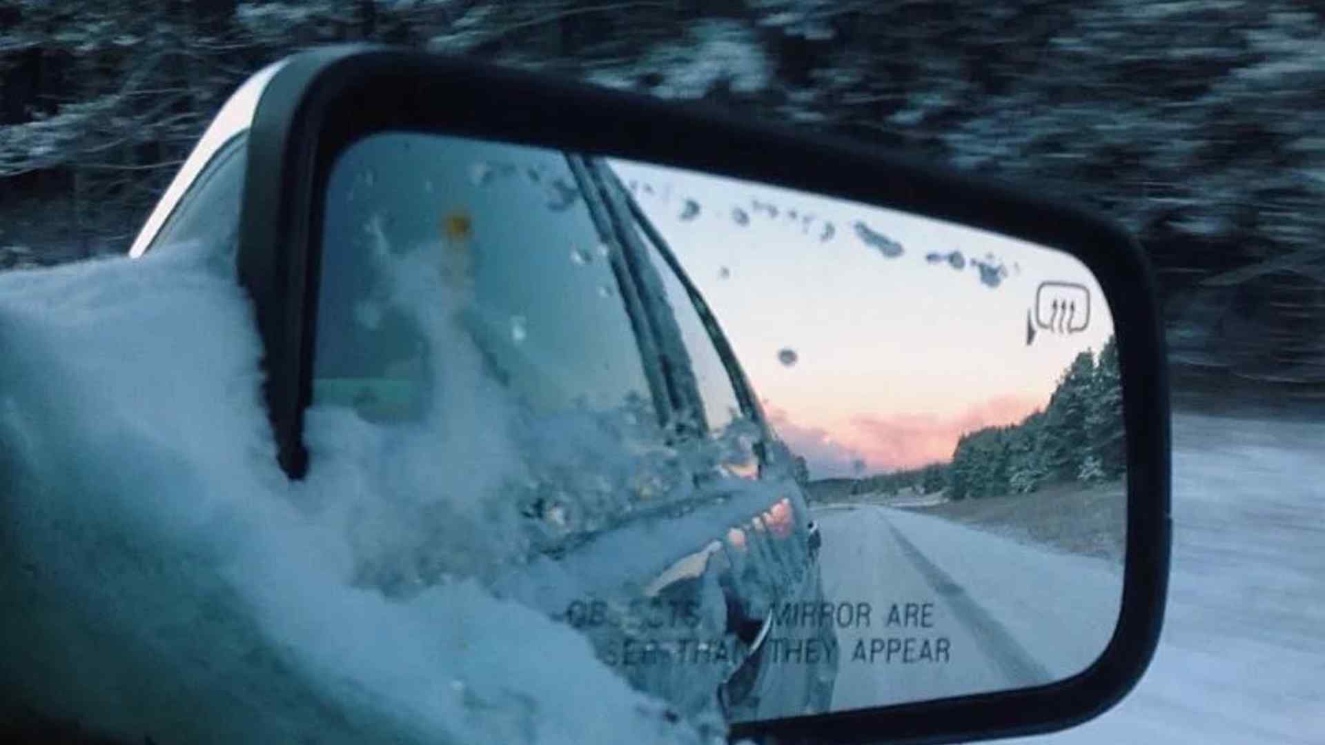 A snowy side mirror on a car