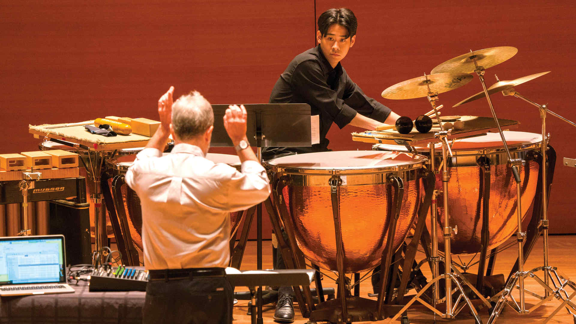 Percussion faculty member Daniel Druckman conducting and percussion student Christopher Choi plays the timpani