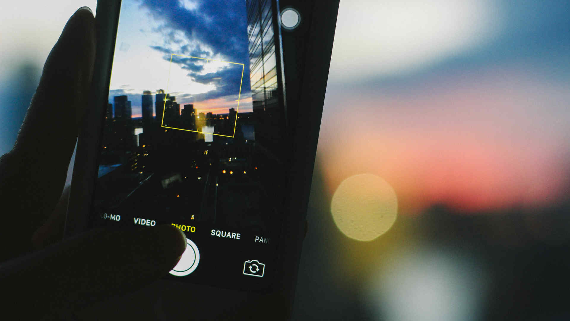 A cellphone taking a photo of a sunset