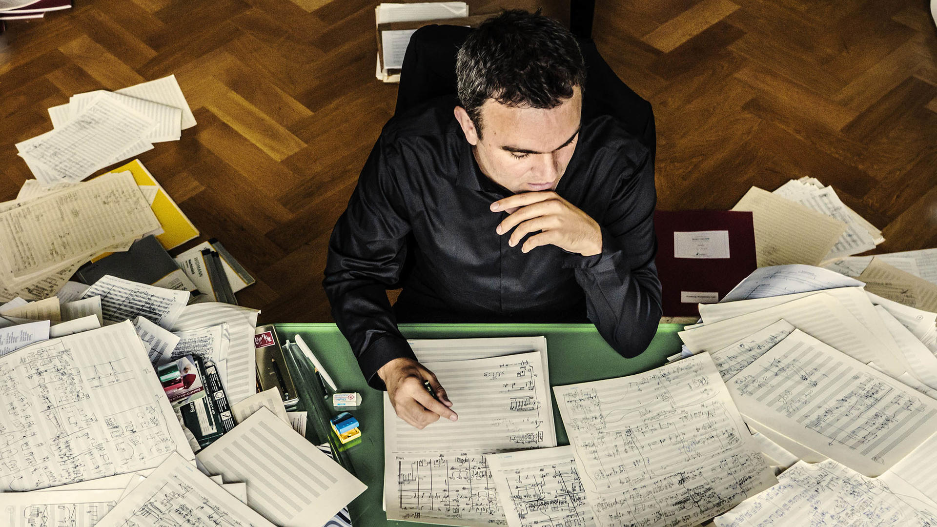 Jörg Widmann at a desk, surrounded by manuscript paper and sheet music