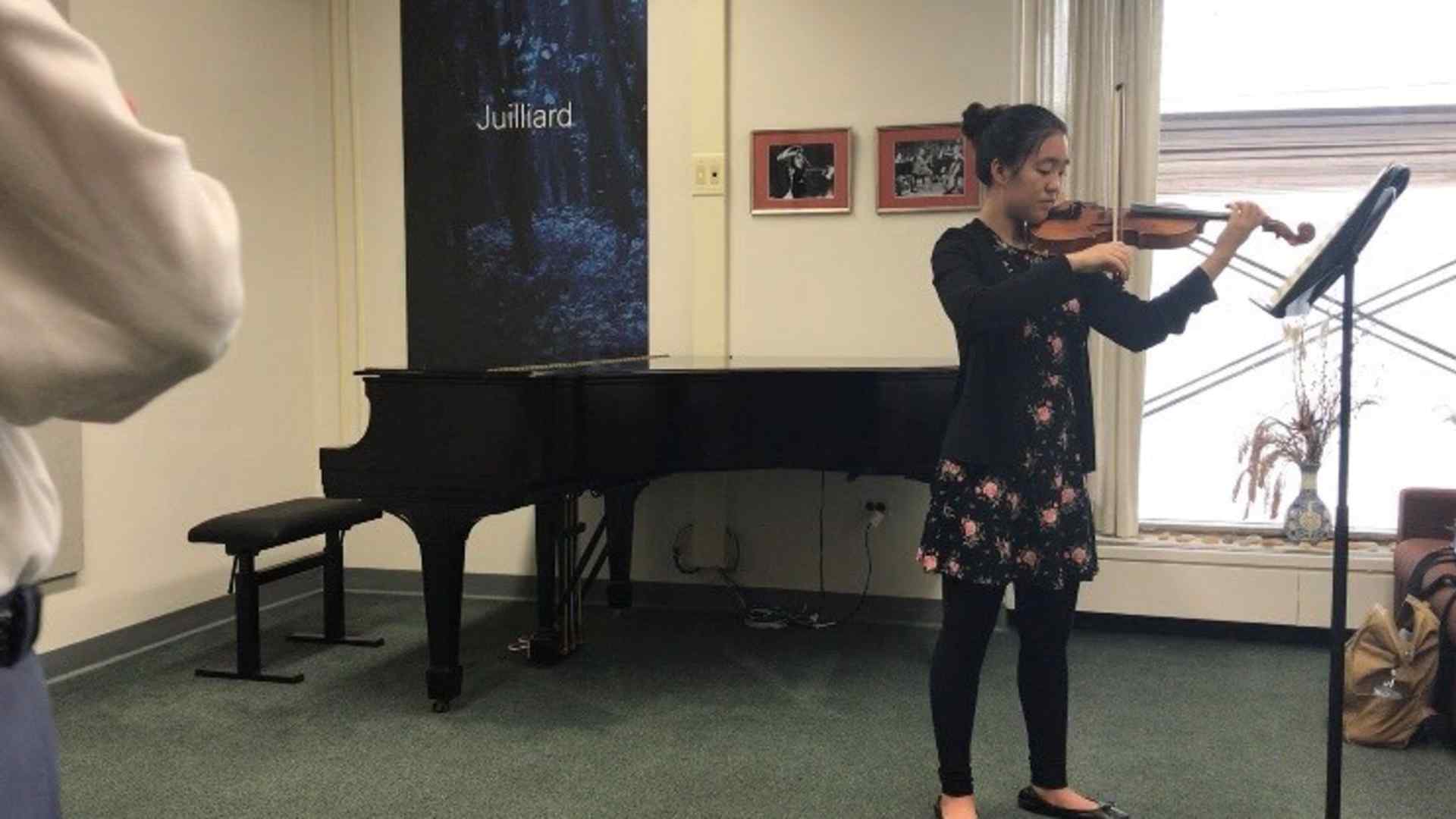 Amy practices violin in a classroom