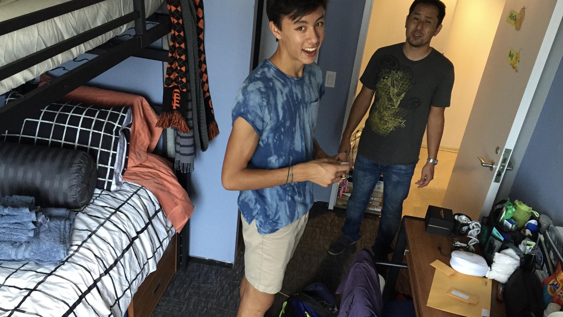 A young Noah stands in a dorm room