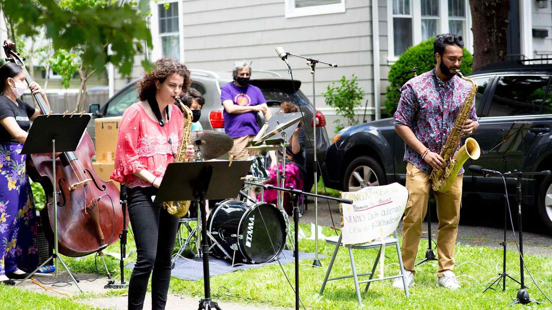 A jazz combo performing outdoors, on the lawn of a suburban home