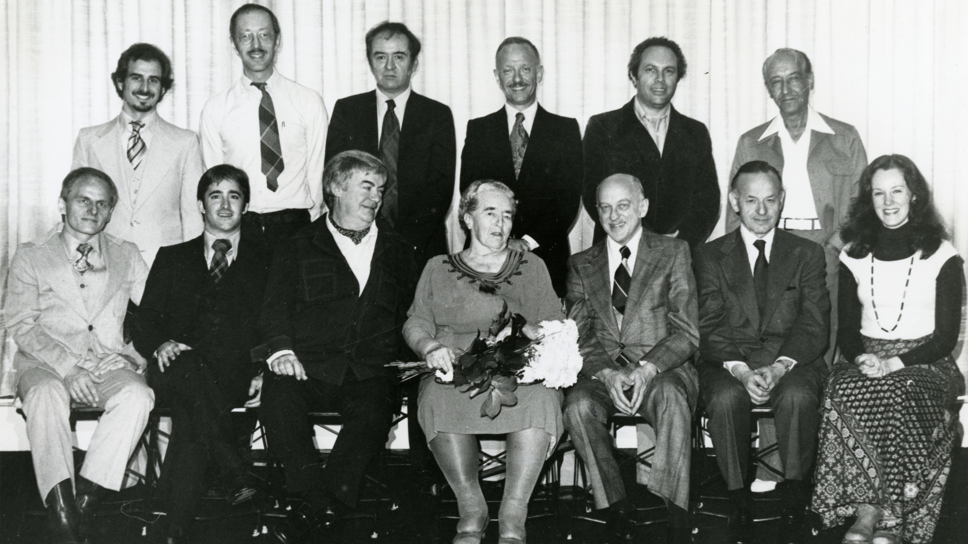 An archival, black and white photo of Mme. Renée Longy is seated center for a portrait style photo with students