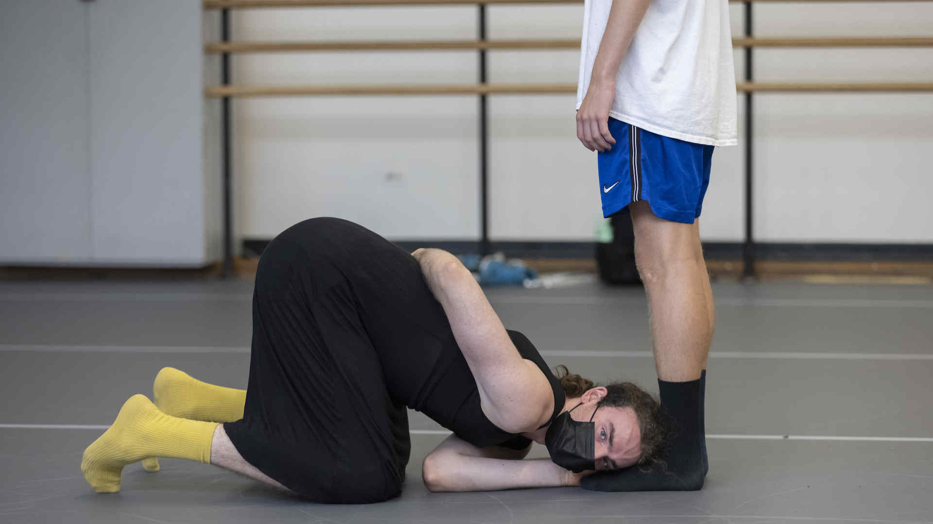 A dancer on the studio floor beside a dancer standing upright