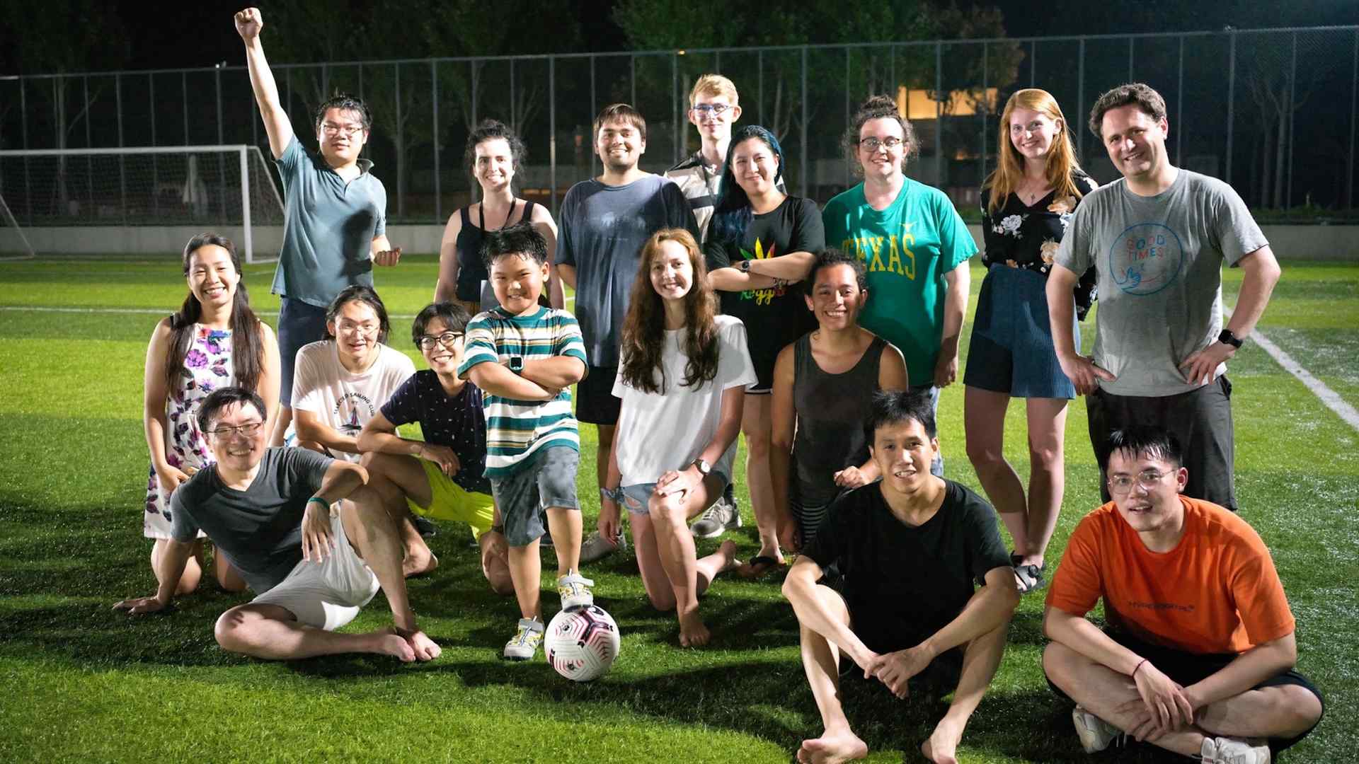 Students posing for a group photo in a field after playing soccer