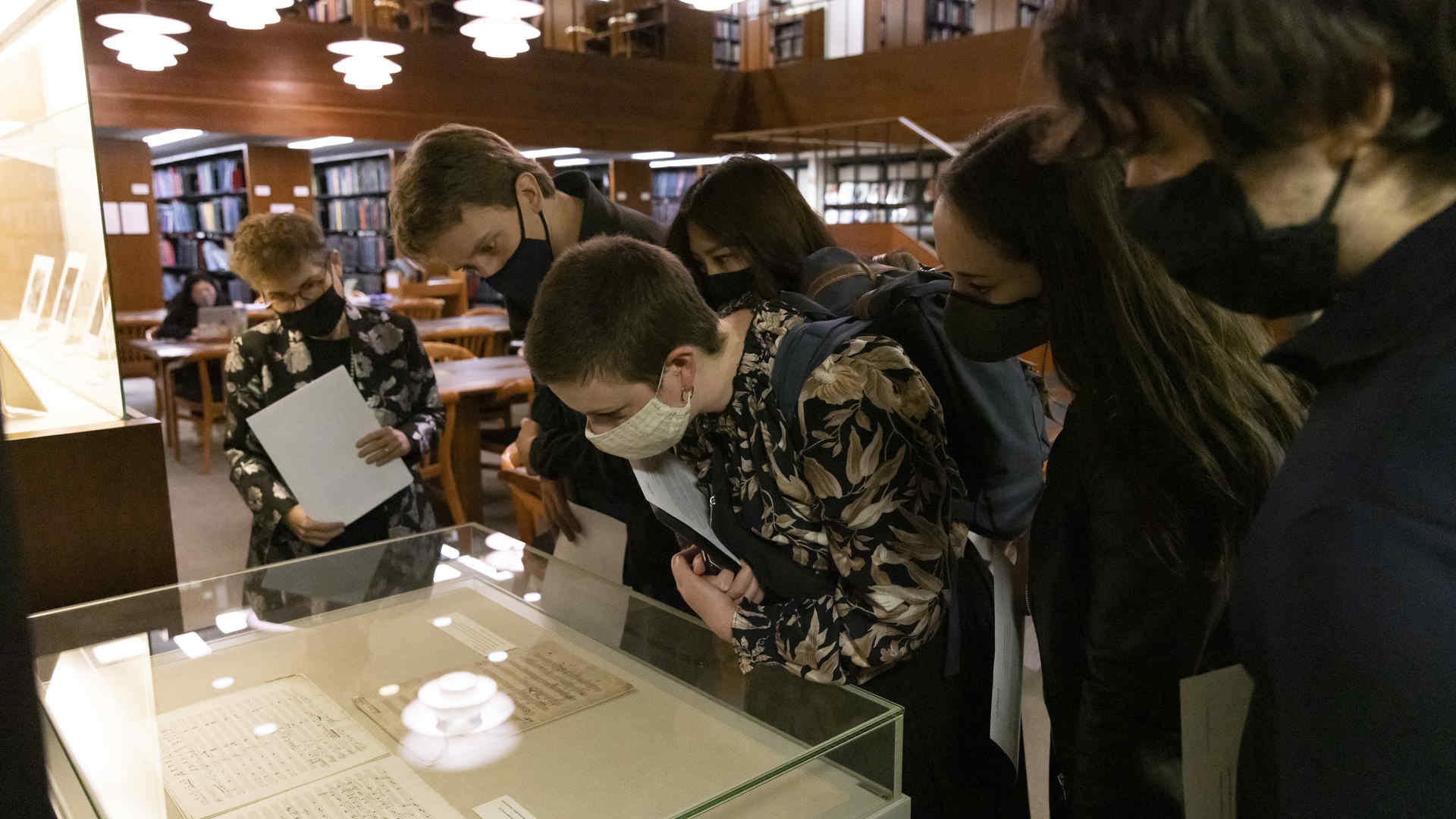 People in Juilliard's library leaning over a glass case examining one of Beethoven's scores