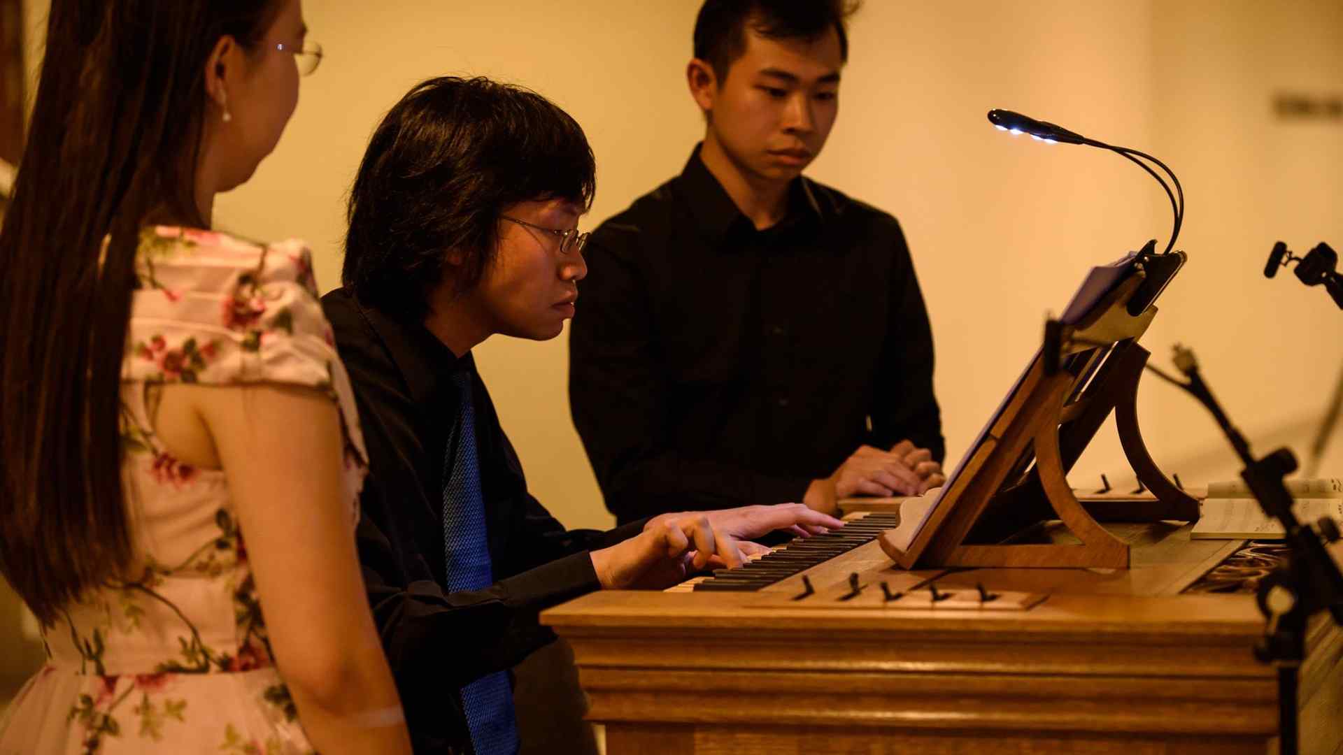 Phoon Yu at a portativ organ in Singapore with colleagues look on