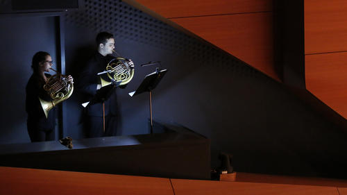 Two French Horn players standing during a performance