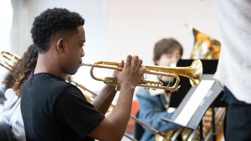 A young man practicing the trumpet in a MAP class