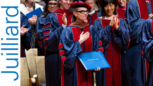 older woman holding a diploma on a stage