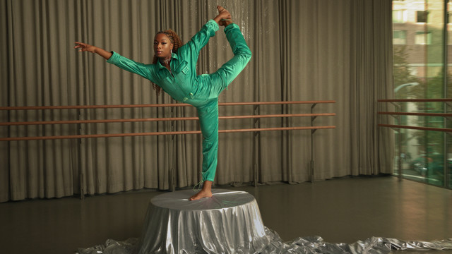 Raven Joseph dressed in a fashionable emerald green jumpsuit posing in a dance studio